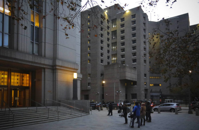 Reporters wait outside federal court for the exit of two jail guards, following their arraignment charge of falsifying prison records about their monitoring of Jeffrey Epstein the night he killed himself at the Metropolitan Correctional Center jail, center, Tuesday Nov. 19, 2019, in New York. (AP Photo/Bebeto Matthews)