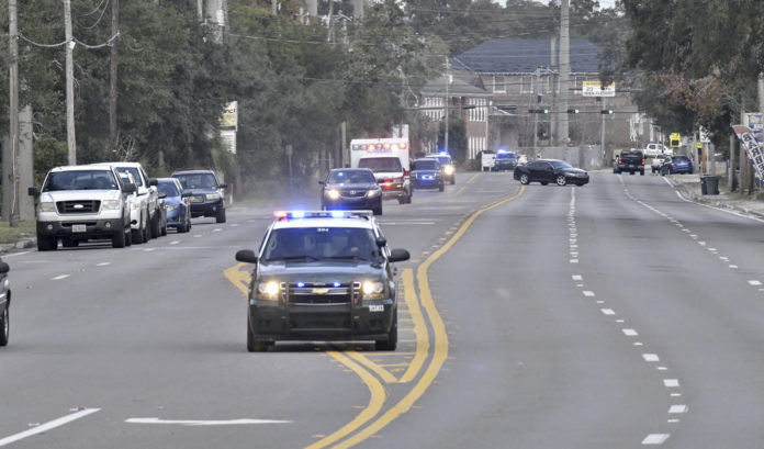 Police cars escort an ambulance after a shooter open fire inside the Pensacola Air Base, Friday, Dec. 6, 2019 in Pensacola, Fla. The US Navy is confirming that a shooter is dead and several injured after gunfire at the Naval Air Station in Pensacola. (Tony Giberson/ Pensacola News Journal via AP)