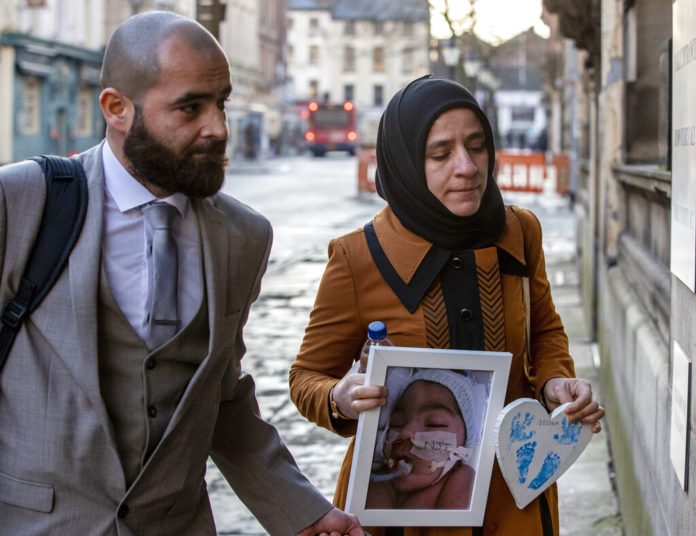 FILE - In this Jan. 20, 2020 file photo, Karwan Ali, left, and Shokhan Namiq, hold a picture of their son, in Preston, England. The parents of a baby who was declared brain dead by doctors has lost the latest round of a legal battle in Britain’s courts to keep him on life support. Britain’s Court of Appeal on Friday, Feb. 14 rejected an attempt by Karwan Ali and Shokhan Namiq to overturn a High Court order that doctors could stop treating their infant son Midrar Ali. (Peter Byrne/PA via AP)