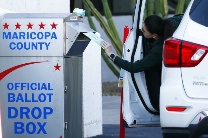 A voter drops off a ballot for the Arizona Democratic presidential preference election Tuesday, March 17, 2020, in Phoenix. (AP Photo/Ross D. Franklin)