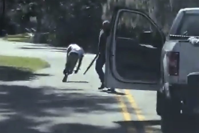 ADDS THAT THE AP HAS NOT BEEN ABLE TO VERIFY THE SOURCE OF THE VIDEO - This image from video posted on Twitter Tuesday, May 5, 2020, purports to show Ahmaud Arbery stumbling and falling to the ground after being shot as Travis McMichael stands by holding a shotgun in a neighborhood outside Brunswick, Ga., on Feb. 23, 2020. The AP has not been able to verify the source of the video. (Twitter via AP)