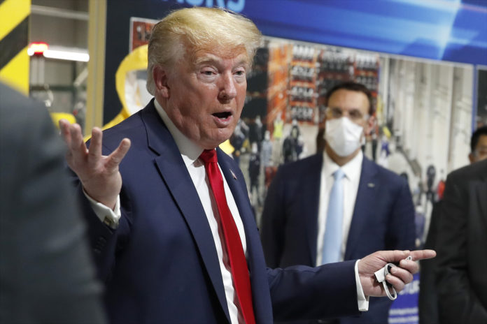 resident Donald Trump holds a face mask in his left hand as speaks during a tour of Ford's Rawsonville Components Plant that has been converted to making personal protection and medical equipment, Thursday, May 21, 2020, in Ypsilanti, Mich. (AP Photo/Alex Brandon)
