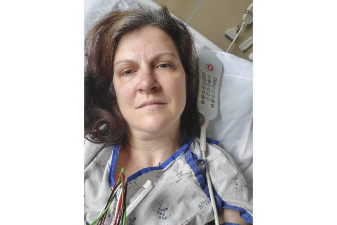 This May 6, 2020 photo provided by Darlene Gildersleeve, 43, of Hopkinton, N.H. shows her at a Manchester, N.H. hospital. Gildersleeve thought she had recovered from COVID-19. Doctors said she just needed rest. And for several days, no one suspected her worsening symptoms were related — until a May 4 video call, when her physician heard her slurred speech and consulted a specialist. “You’ve had two strokes,’’ a neurologist told her at the hospital. (Darlene Gildersleeve via AP)