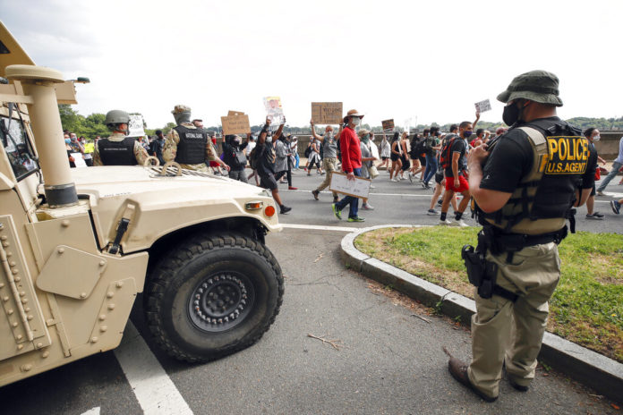 DC National Guard soldiers and other law enforcement personnel watch as demonstrators protest Saturday, June 6, 2020, along Independence Avenue in Washington, over the death of George Floyd, a black man who was in police custody in Minneapolis. Floyd died after being restrained by Minneapolis police officers. (AP Photo/Alex Brandon)
