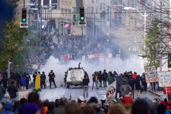FILE - In this Nov. 30 1999, file photo, Seattle police use tear gas to push back World Trade Organization protesters in downtown Seattle. Seattle has a long history of demonstrations, stretching back to labor movements before World War I. (AP Photo/Eric Draper, File)