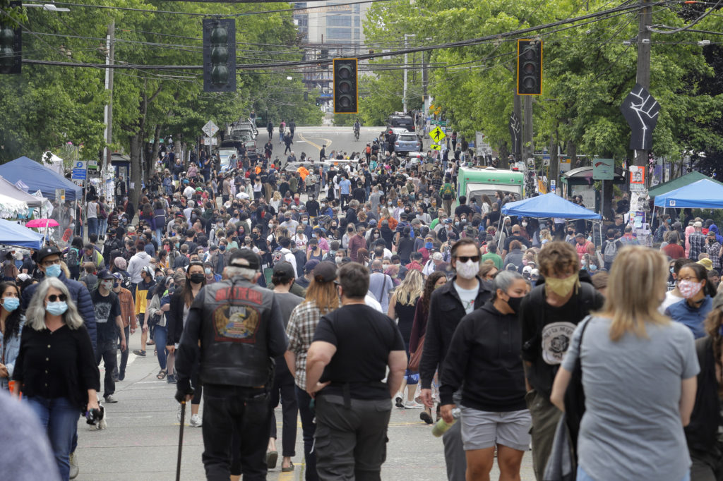People fill a street Sunday, June 14, 2020, inside what has been named the Capitol Hill Occupied Protest (CHOP) zone in Seattle. Protesters calling for police reform and other demands have taken over several blocks near downtown Seattle after officers withdrew from a police station in the area following violent confrontations. Hundreds of people came out Sunday to check out the scene. (AP Photo/Ted S. Warren)