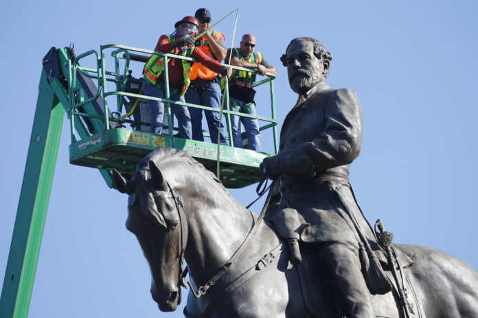 FILE - In this June 8, 2020 file photo an inspection crew from the Virginia Department of General Services takes measurements as they inspect the statue of Confederate Gen. Robert E. Lee on Monument Avenue in Richmond, Va. Six property owners along Monument Avenue in Virginia's capital city filed a lawsuit Monday, June 15, 2020 seeking to stop Gov. Ralph Northam's administration from removing the towering statue. (AP Photo/Steve Helber, file)