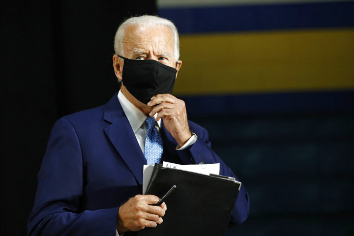 Democratic presidential candidate, former Vice President Joe Biden puts on a face mask to protect against the spread of the new coronavirus as he departs after speaking at Alexis Dupont High School in Wilmington, Del., Tuesday, June 30, 2020. (AP Photo/Patrick Semansky)