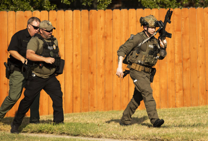 Police officers work near the house in Cedar Park, Texas, where a person remained barricaded Sunday, Aug. 16, 2020. Three police officers were shot, authorities said. The officers are in stable condition at a local hospital, police said on Twitter. (Jay Janner/Austin American-Statesman via AP)