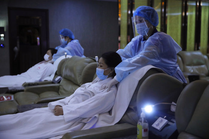 Staff members wearing protective suits demonstrate their safety measures to media as they hope the government allowing their massage parlours to reopen in Hong Kong, Friday, Aug. 28, 2020. Businesses such as massage parlours was forced to close to prevent the spread of COVID-19 as part of social distancing measures. The city's economy contracted 9% in the second quarter of this year, marking a full year of recession due to last year's anti-government protests and the pandemic. (AP Photo/Kin Cheung)