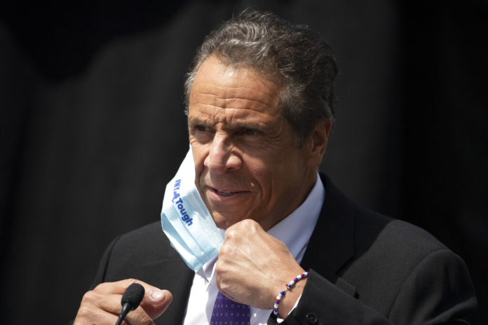 FILE - In this June 15, 2020, file photo, New York Gov. Andrew Cuomo removes a mask as he holds a news conference in Tarrytown, N.Y. On Wednesday, Aug. 26, 2020, the Justice Department sent letters to the governors of New York and three other Democratic-led states, seeking data on whether they violated federal law by ordering public nursing homes to accept recovering COVID-19 patients from hospitals, actions that have been criticized for potentially fueling the spread of the virus. (AP Photo/Mark Lennihan, File)