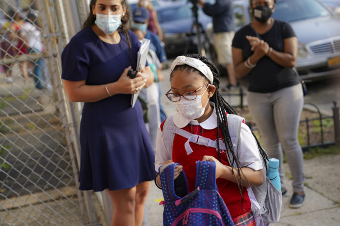 FILE - In this Sept. 9, 2020, file photo, students wear protective masks as they arrive for classes at the Immaculate Conception School while observing COVID-19 prevention protocols, in the Bronx borough of New York. (AP Photo/John Minchillo)