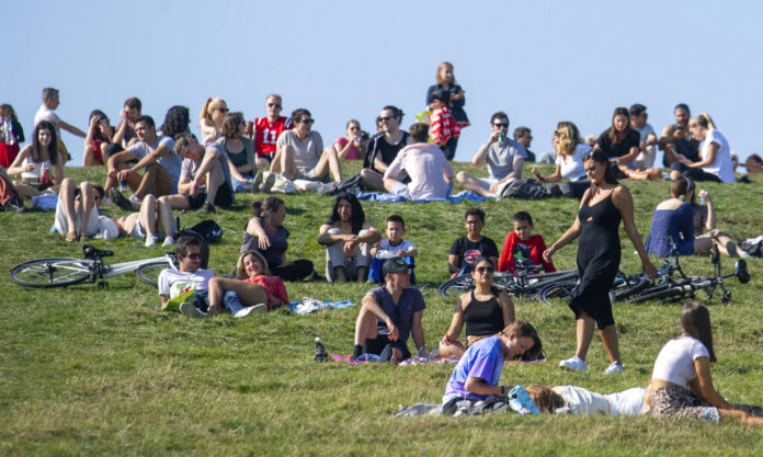 People enjoying the autumn sunshine on Primrose Hill, London, Sunday, Sept. 13, 2020. From Monday, social gatherings of more than six people will be banned in England — both indoors and outdoors — and Boris Johnson hinted that such restrictions will potentially remain in place until or through Christmas. (Dominic Lipinski/PA via AP)