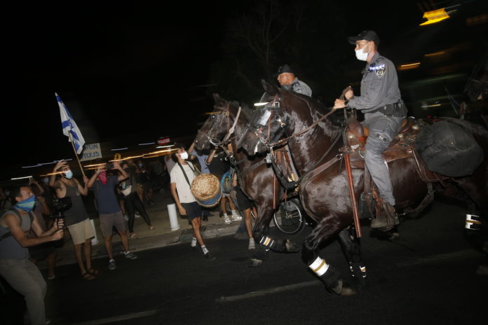 Israeli police officers on horses open the road during a demonstration against lockdown measures that protesters believe are aimed at curbing protests against prime minister Benjamin Netanyahu Tel Aviv, Israel, Saturday, Oct. 3, 2020. (AP Photo/Ariel Schalit)