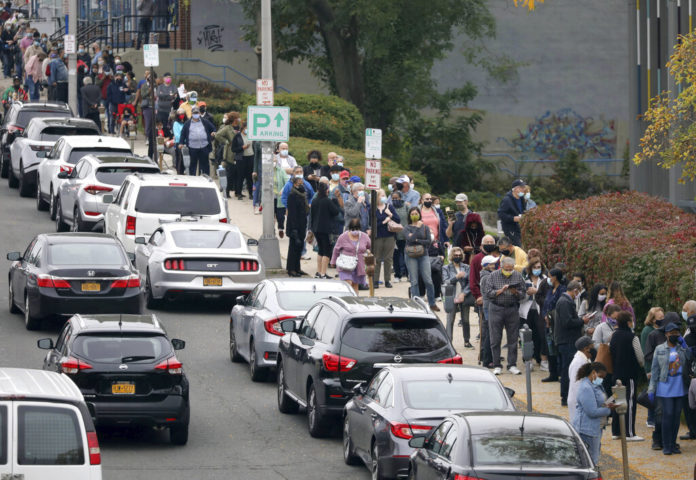 Voters line up in front of the Yonkers Public Library in Yonkers, N.Y., on Saturday, Oct. 24, 2020 as the first day of early voting in the presidential election begins across New York state. (Mark Vergari/The Journal News via AP)