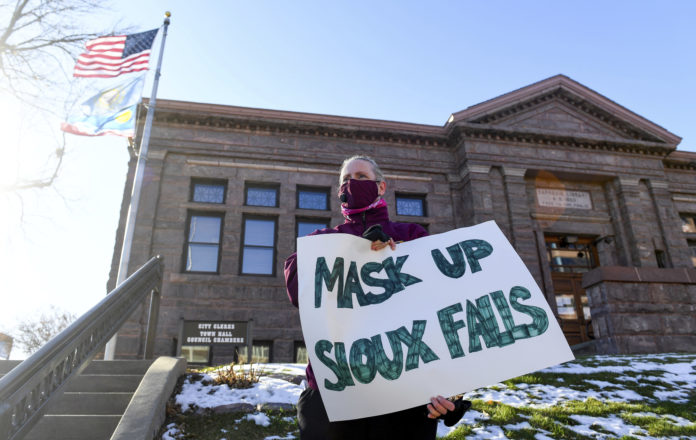 Jenae Ruesink holds a sign demanding a mask mandate from city council on Monday, Nov. 16, 2020 outside Carnegie Town Hall in Sioux Falls, S.D. (Erin Bormett/The Argus Leader via AP)