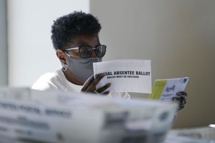 A worker at the Fulton County Board of Registration and Elections works to process absentee ballots at the State Farm Arena Monday, Nov. 2, 2020, in Atlanta. (AP Photo/John Bazemore)
