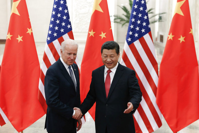 FILE - In this Dec. 4, 2013, file photo, Chinese President Xi Jinping, right, shakes hands with then U.S. Vice President Joe Biden as they pose for photos at the Great Hall of the People in Beijing. (AP Photo/Lintao Zhang, Pool, File)