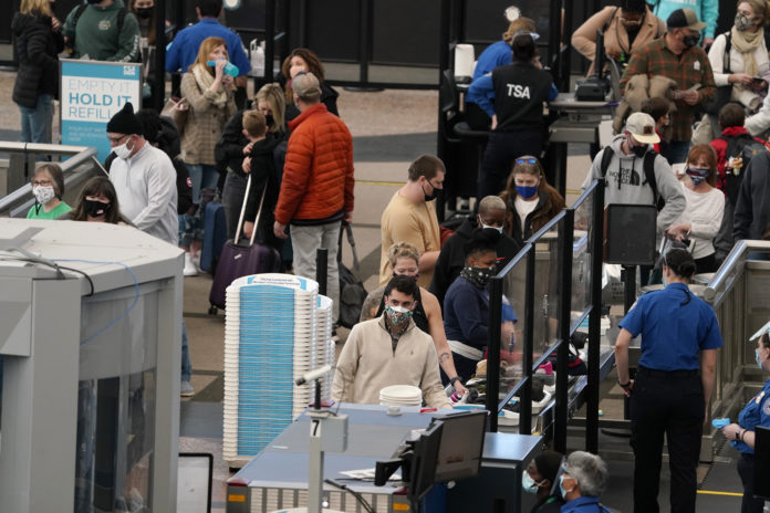 FILE - In this Thursday, Feb. 18, 2021, file photo, travelers wear face coverings as they queue up at the north security checkpoint in the main terminal of Denver International Airport, in Denver. Major U.S. airlines say they will ask passengers on flights to the United States for information that public health officials could use for COVID-19 contact tracing. The trade group Airlines for America said Friday, Feb. 19, that the carriers will turn over the information to the Centers for Disease Control and Prevention. (AP Photo/David Zalubowski, File)