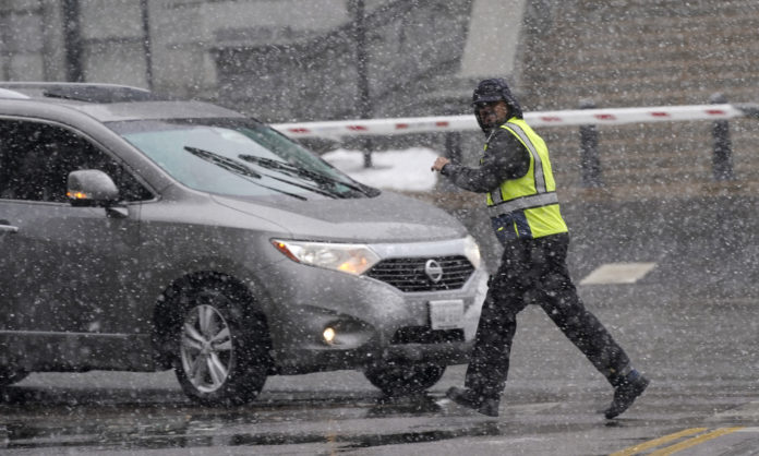 A pedestrian hurries across the intersection of Grant Street and Colfax Avenue as a snowstorm sweeps over the intermountain West Saturday, March 13, 2021, in Denver. Forecasters were predicting up to three feet of snow from the lumbering storm, which started slowly around the noon hour Saturday. (AP Photo/David Zalubowski)